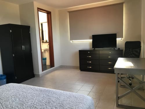 Habitación espaciosa en Hotel El Candelero en Yuriria con muebles negros, TV y comodidades modernas