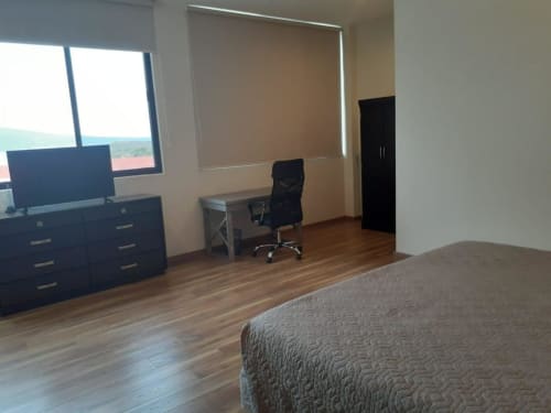 Habitación moderna en Hotel El Candelero en Yuriria con escritorio, TV y vista a la piscina desde la ventana