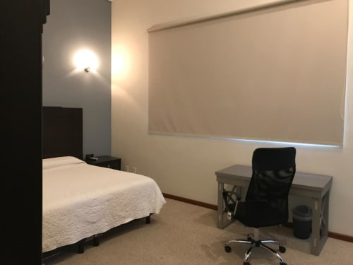 Habitación del Hotel El Candelero en Yuriria con cama, escritorio, silla y ventana con persiana