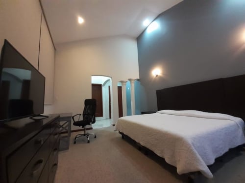 Habitación moderna del hotel El Candelero en Yuriria con cama, TV, escritorio de trabajo e iluminación ambiental