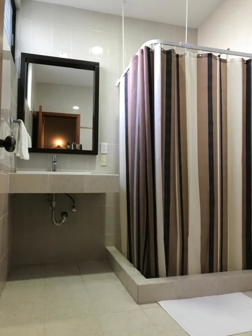 Baño moderno del Hotel El Candelero en Yuriria con cortina de ducha a rayas y espejo enmarcado