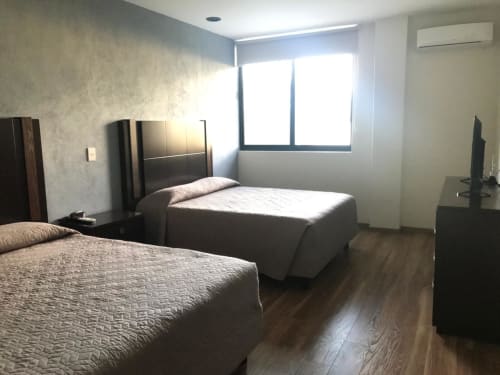 Habitación de hotel con cama twin en El Candelero, Yuriria, con muebles de madera oscura y amplia ventana