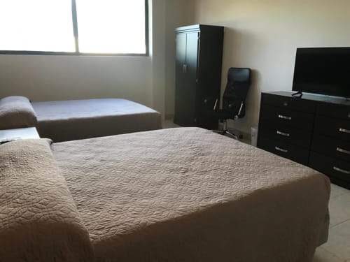 Habitación del Hotel El Candelero en Yuriria con dos camas, TV, armario y tocador