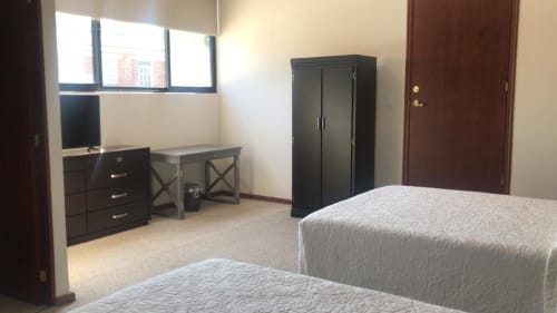 Habitación espaciosa en Hotel El Candelero en Yuriria con dos camas, armario oscuro, escritorio y ventanas