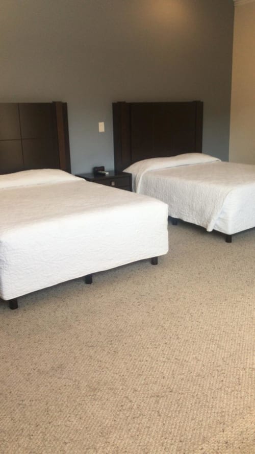 Dos camas gemelas con ropa de cama blanca en una habitación moderna del Hotel El Candelero en Yuriria, México