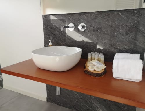 Lavatório moderno em Em Xisto com cuba branca, painel de pedra escura, bancada em madeira e itens de banho na montanha