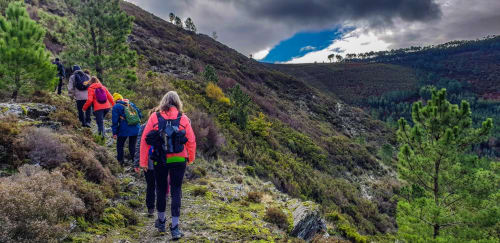 Caminhantes em trilha de montanha perto do hotel Em Xisto em Góis, Portugal, com encostas florestadas