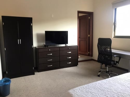 Habitación del Hotel El Candelero Yuriria con muebles negros, TV, escritorio, silla de oficina y ventana