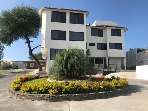 Hotel El Candelero en Yuriria cuenta con modernos edificios blancos de ventanas oscuras y un colorido paisajismo