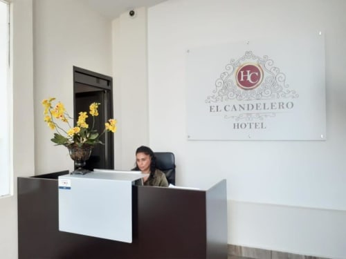Recepción del Hotel El Candelero en Yuriria con recepcionista y flores amarillas