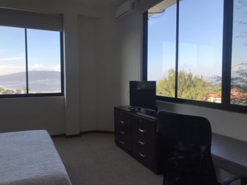 Moderno dormitorio en el Hotel El Candelero de Yuriria con vistas panorámicas del lago y las montañas a través de grandes ventanales