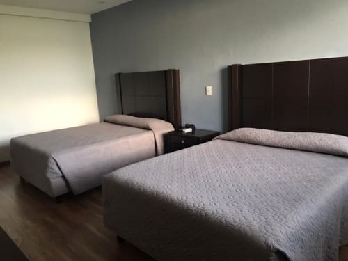 Habitación moderna del hotel El Candelero en Yuriria con dos camas queen y cabeceros de madera oscura