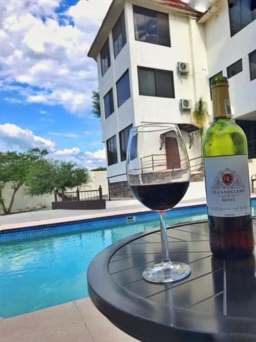 Copa de vino y botella en la piscina del Hotel El Candelero en Yuriria, México