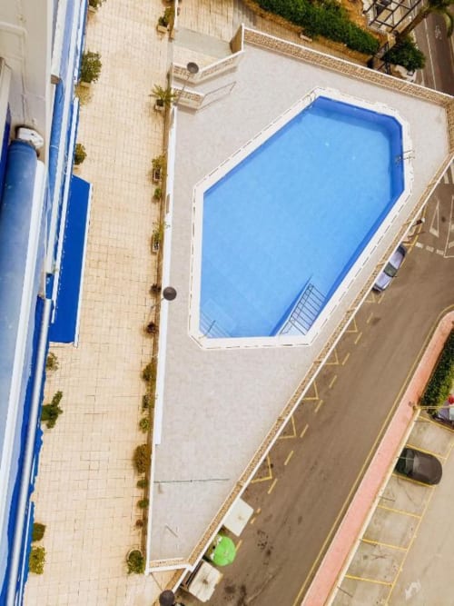 Aerial view of Tads Holiday Lets apartment pool in Benidorm with blue octagonal swimming pool, terrace, and parking area