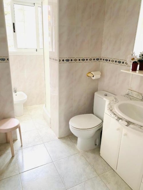 Clean bathroom in Benidorm apartment with toilet, sink, washing machine, and shower enclosure