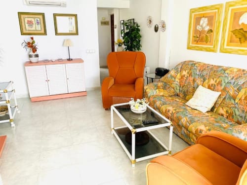 Living room at Tads Holiday Lets beach apartment in Benidorm with orange chairs, patterned sofa, and sea view decor