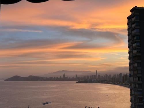Golden sunset over Benidorm beach with city skyline, sea view from apartment balcony