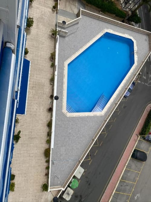 Aerial view of octagonal swimming pool at Tads Holiday Lets in Benidorm with surrounding deck and parking area