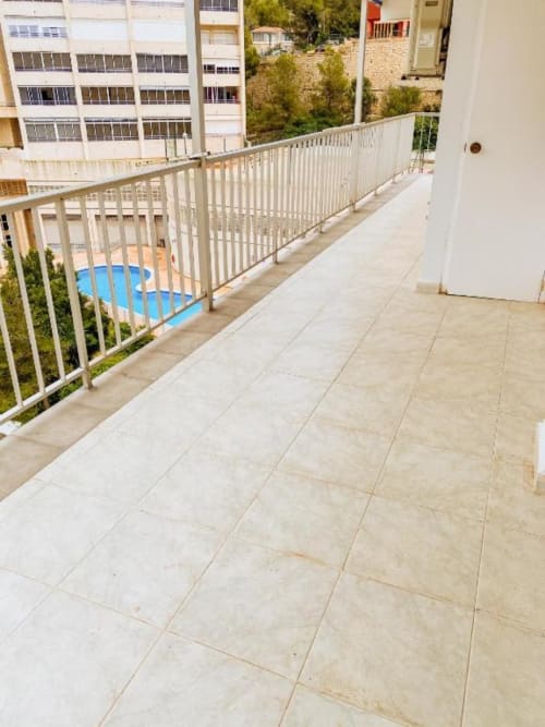 Spacious balcony with sea view at Tads Holiday Lets Benidorm apartment, white railing overlooking pool and city buildings