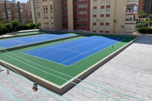 Blue and green sports courts in Benidorm apartment complex courtyard surrounded by residential buildings