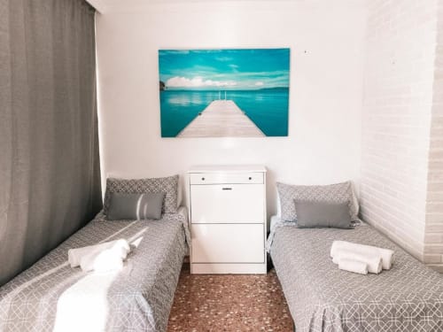 Twin bedroom at Lidersol Apartments in Benidorm with turquoise sea pier artwork above beds