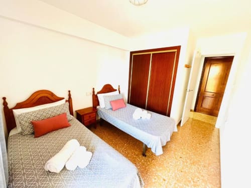 Twin bedroom in Mariscal Apartments, Benidorm with wooden beds, terracotta flooring, and wardrobe doors