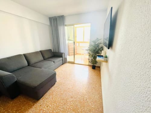 Modern living room with gray sofa, TV, and balcony at Mariscal Apartments, Benidorm