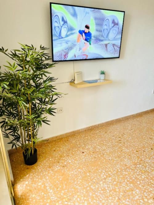Modern living room at Mariscal Apartments in Benidorm with flat screen TV, bamboo plant, and tiled flooring