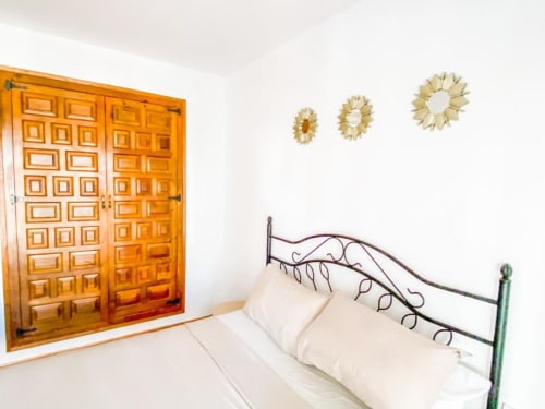Modern bedroom at Tads Holiday Lets in Benidorm with ornate wooden wardrobe, wrought iron bed, white linens, and decorative