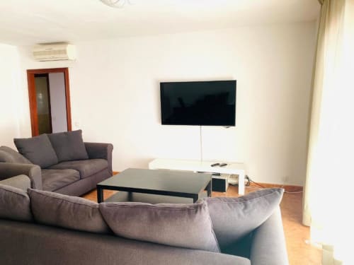 Modern living room at Tads Holiday Lets Zafiro Apartments in Benidorm with gray sofas, black coffee table, and wall-mounted