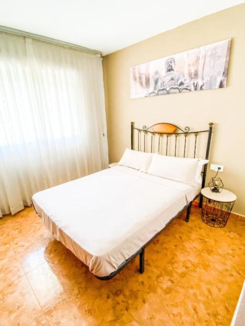 Modern bedroom in Zafiro Apartments, Benidorm with wrought iron bed, white linens, and garden views
