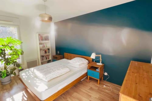Chambre moderne à la Conciergerie Pour Tous By Patty à Darazac avec lit en bois, mur bleu canard et lumière naturelle