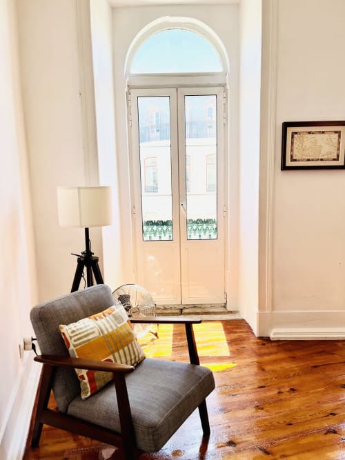 Modern apartment lounge at Royal Prince Garden in Lisbon with mid-century chair, wooden floors and arched doors opening to
