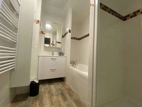 Salle de bain moderne de la villa Le Domaine du Bez à Saint Laurent d'Olt avec vasque blanche, baignoire et sol aspect bois
