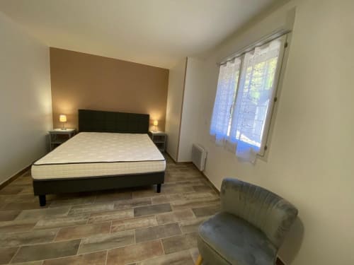 Chambre moderne à la villa Le Domaine du Bez à Saint Laurent D'olt avec lit queen-size, lampes de chevet, fauteuil et vue sur les montagnes