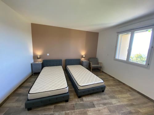 Deux lits simples dans une chambre de villa moderne du Domaine du Bez avec vue sur les montagnes et mobilier contemporain