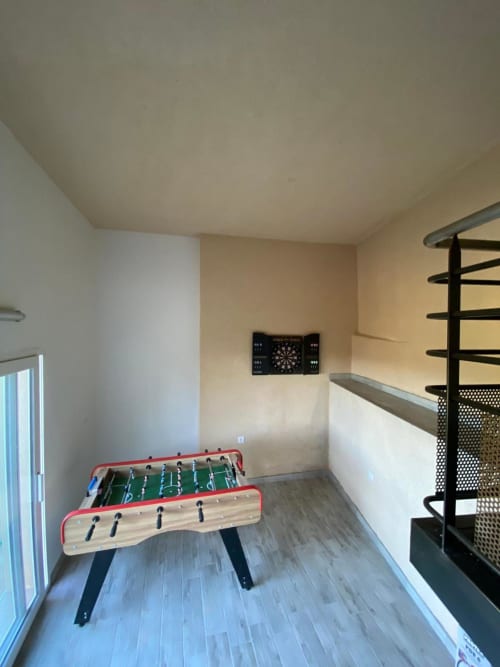 Salle de loisirs avec baby-foot, fléchettes et escalier en spirale à la villa Le Domaine du Bez