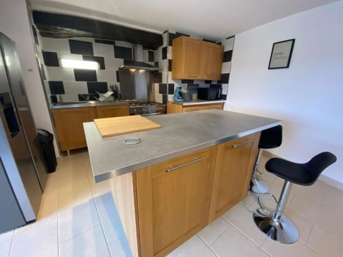 Cuisine moderne avec placards en bois, électroménagers en acier inoxydable et îlot de La villa du Domaine du Bez