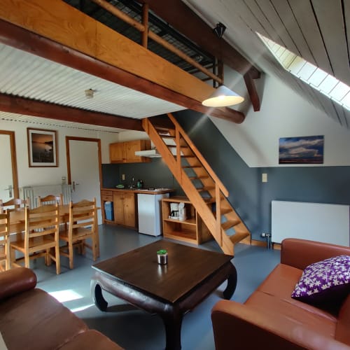 Open-plan appartement in La Ferme De Werpin met houten balken, eethoek, keuken en zithoek met bruin leer