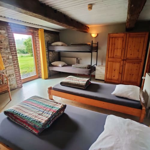 Spacious ground floor apartment bedroom at La Ferme De Werpin with wooden beds, bunk beds, garden view through glass doors,