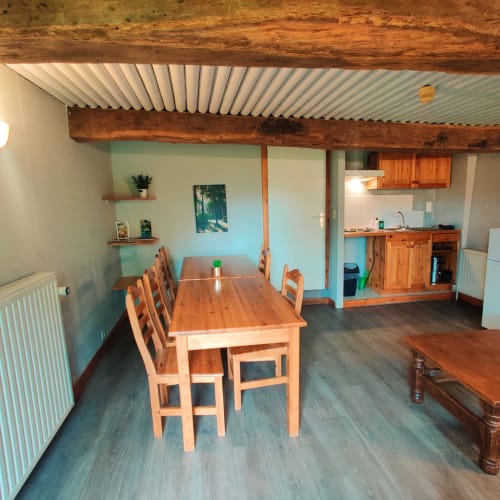 Open-plan dining and kitchen area in La Ferme De Werpin apartment, Hotton with wooden beams, dining table, and modern