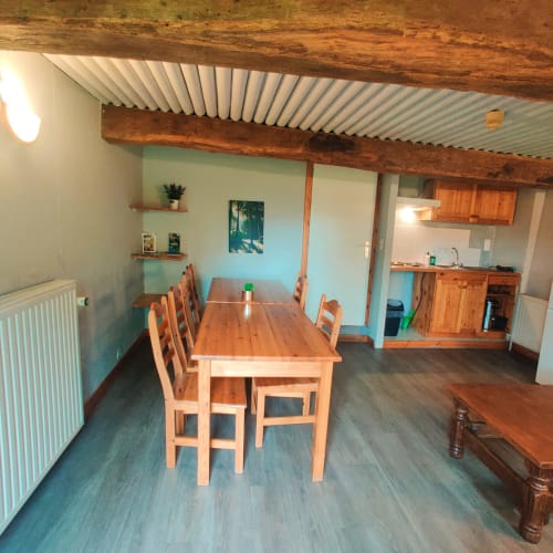Spacious dining and kitchen area in Hotton apartment with wooden beams, table, chairs, and garden view