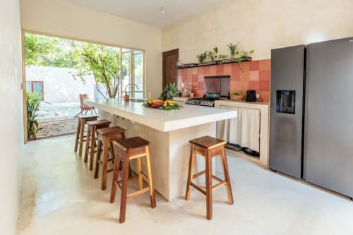 Cocina moderna con isla, azulejos rojos en el salpicadero y vista a la piscina en la casa Casa Tuch en Mérida