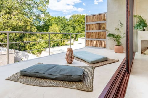 Terraza serena en la azotea de la Casa Tuch en Mérida con cojines de meditación, plantas en maceta y vistas del exuberante jardín.