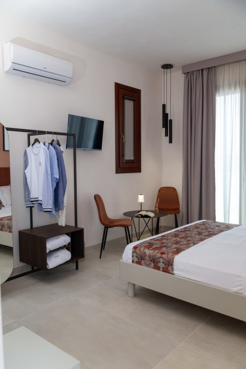 Modern hotel room at Altavilla Boutique Holidays House in Marsala with queen bed, TV, seating area, and sea view balcony