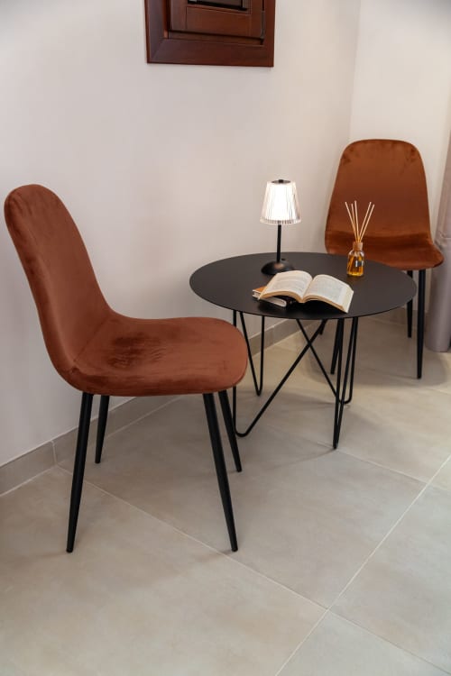 Modern reading nook with rust velvet chairs, black round table, lamp, and open book in Constance Queen Room at Altavilla