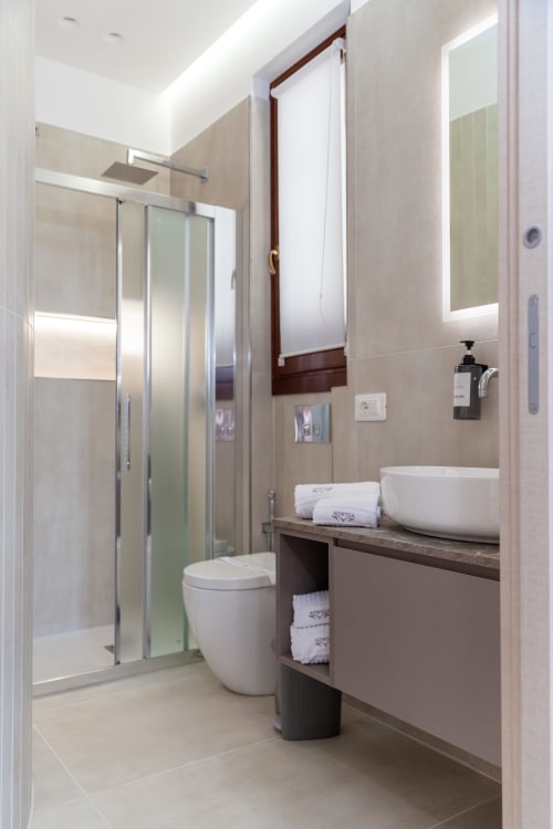 Modern bathroom at Altavilla Boutique Holidays House with vessel sink, shower enclosure, and white towels
