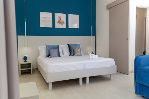 Camera moderna presso Altavilla Boutique Holidays House a Marsala con letto bianco, parete azzurra e arredi contemporanei