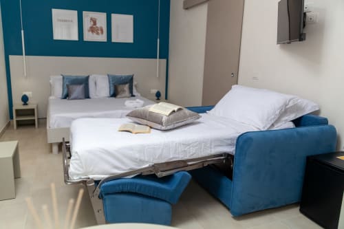 Deluxe Room at Altavilla Boutique Holidays House in Marsala features modern bed and blue seating with white pillows