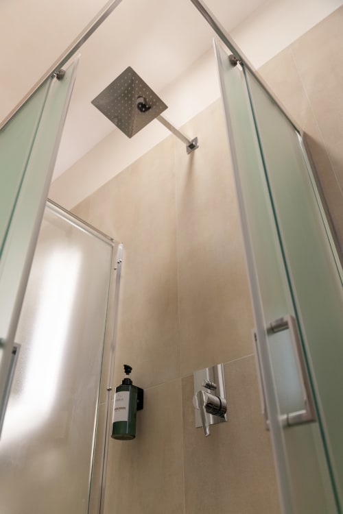 Modern shower enclosure with rainfall showerhead in Altavilla Boutique hotel's Deluxe Room, Marsala